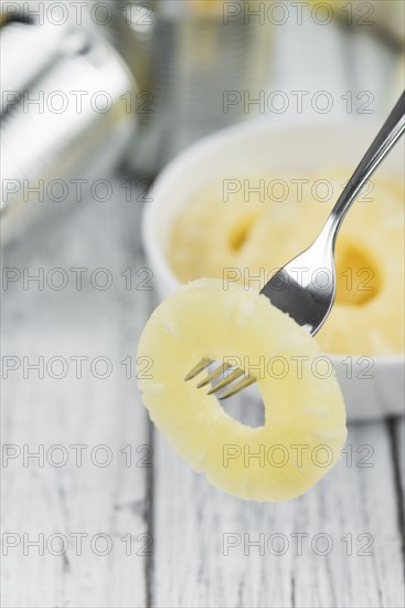 Preserved Pineapple Rings on an old wooden table as detailed close-up shot, selective focus