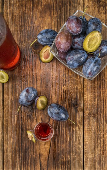 Plum Liqueur on rustic wooden background as close-up shot