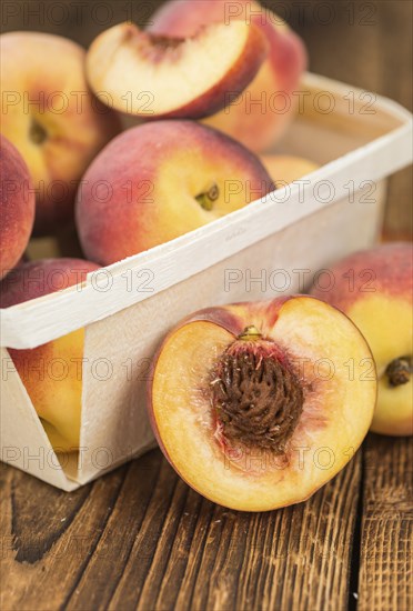 Fresh Peaches as high detailed close-up shot on a vintage wooden table, selective focus