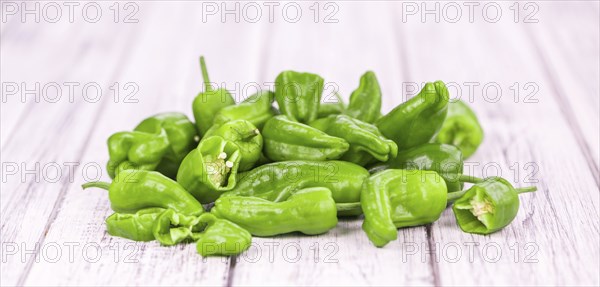 Raw Pimientos on rustic wooden background as close-up shot