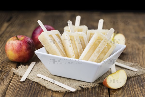 Apple Popsicles on an old wooden table (close-up shot, selective focus)