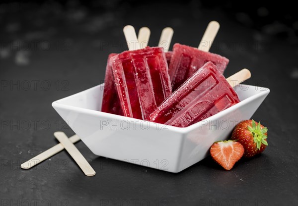 Strawberry Popsicles (close-up shot, selective focus) on a rustic background