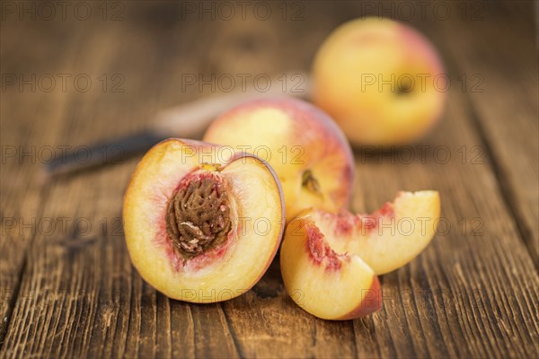 Fresh Peaches as high detailed close-up shot on a vintage wooden table, selective focus