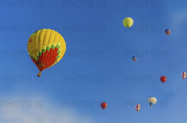 Several hot air balloons of various colors floating in a clear blue sky, Belarus, Minsk, Europe