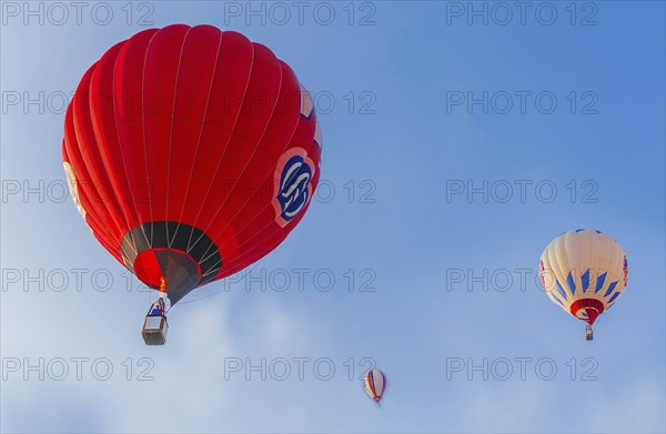 Hot air balloons of red and white colors float against a clear blue sky, Belarus, Minsk, Europe
