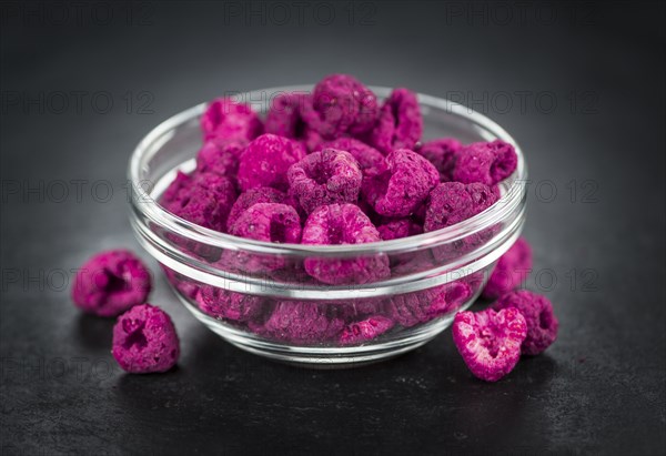 Portion of Dried Raspberries as detailed close up shot on a slate slab, selective focus