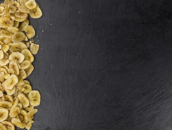 Portion of Dried Banana Chips on a rustic slate slab, selective focus, close-up shot