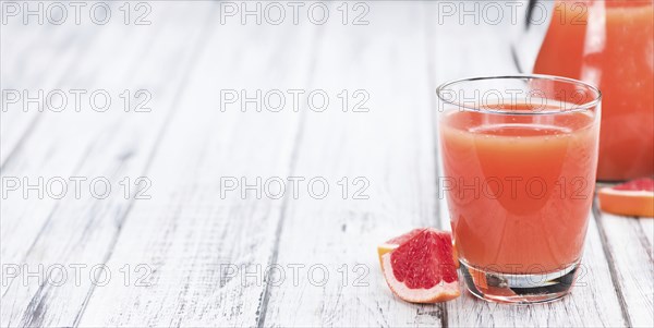 Some freshly squeezed Grapefruit Juice on a vintage background (close-up shot, selective focus)