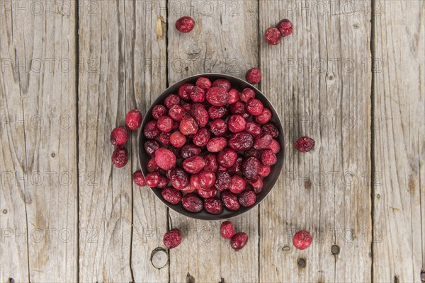 Healthy Cranberries (dried) on a wooden table as detailed close-up shot (selective focus)