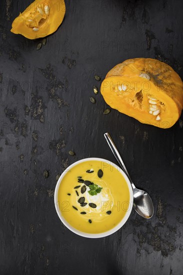 Portion of fresh made Pumpkin Soup (close-up shot) on rustic background