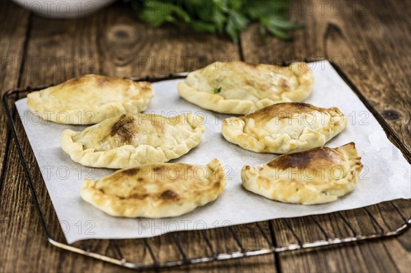 Wooden table with fresh homemade Empanadas (detailed close-up shot, selective focus)