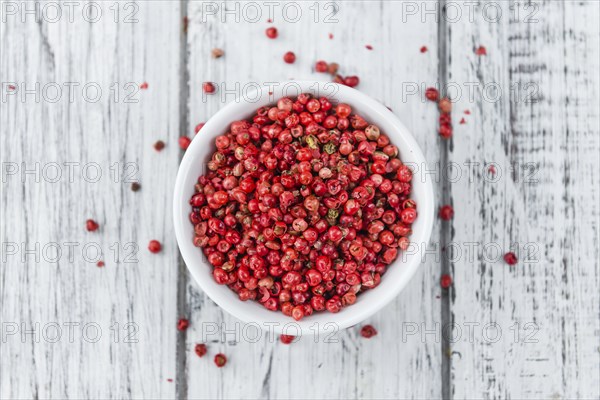 Pink Peppercorns on an old wooden table as detailed close-up shot, selective focus