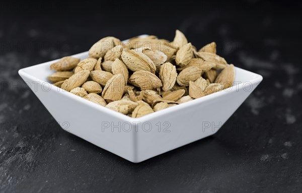 Roasted and salted Almonds (with shell) on a vintage background (close-up shot)