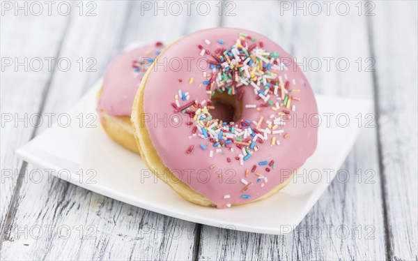 Portion of pink glazed Donuts (detailed close-up shot)