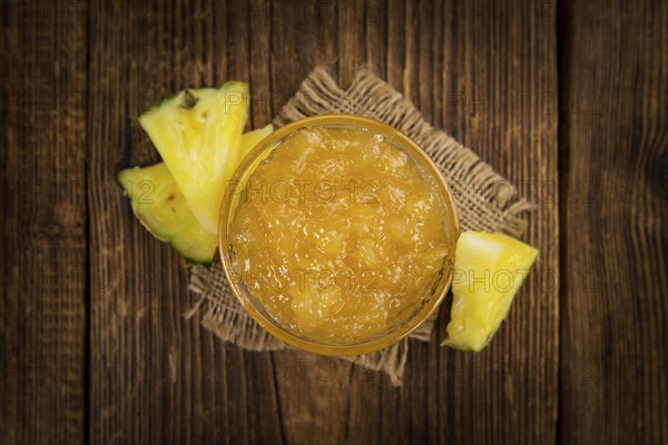 Pineapple Jam as high detailed close-up shot on a vintage wooden table, selective focus