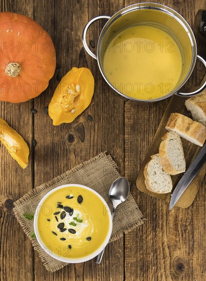 Portion of fresh made Pumpkin Soup (close-up shot) on rustic background