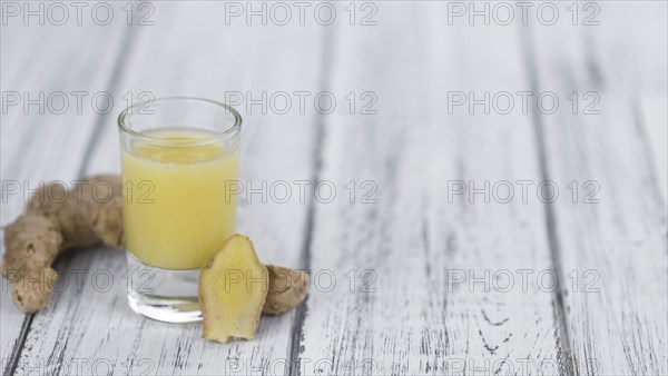 Healthy Ginger Sap on a wooden table as detailed close-up shot (selective focus)