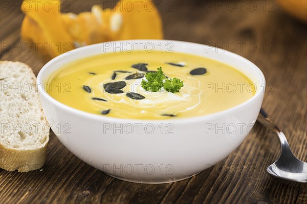 Portion of fresh made Pumpkin Soup (close-up shot) on rustic background