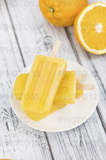 Some fresh made Popsicles (close-up shot, selective focus) on a wooden background