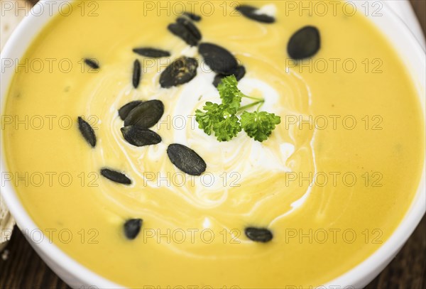 Fresh made Pumpkin Soup (close-up shot) on a vintage background (selective focus)