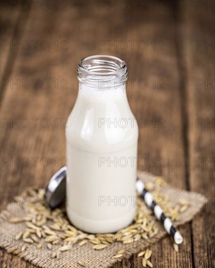 Healthy Oat Milk on a wooden table as detailed close-up shot (selective focus)