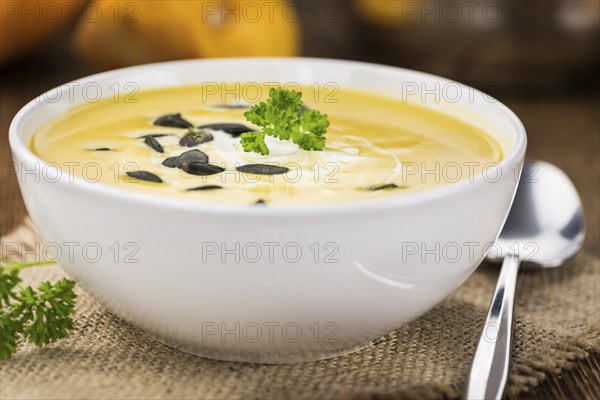 Fresh made Pumpkin Soup (close-up shot) on a vintage background (selective focus)