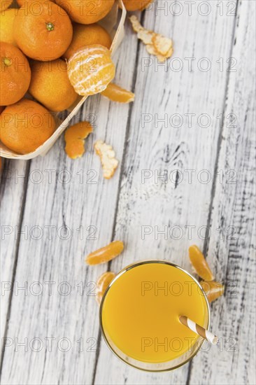 Wooden table with fresh homemade Tangerine Juice (close-up shot, selective focus)