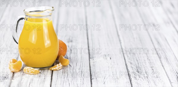 Wooden table with fresh homemade Tangerine Juice (close-up shot, selective focus)