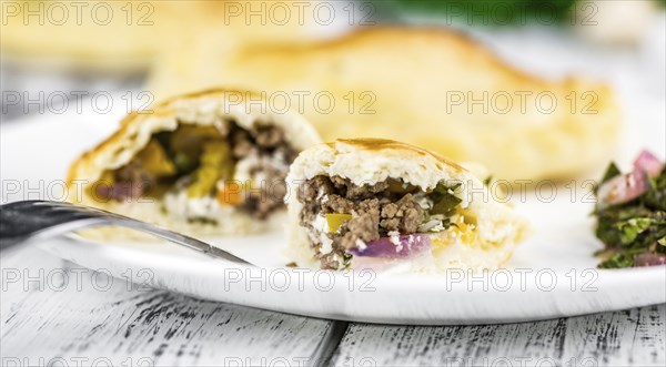Wooden table with fresh homemade Empanadas (detailed close-up shot, selective focus)