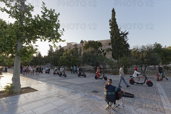Row of tourists riding on e-chopper on Dionysiou Areopagitou, pedestrian street with view of the