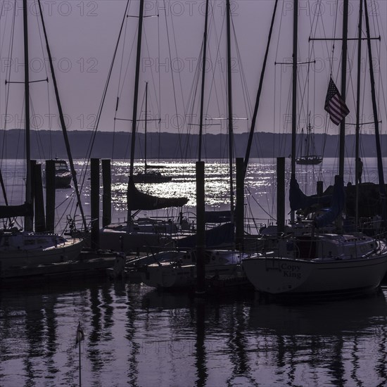 Sailboats in silhouette at anchor with a purple sunrise. Niantic, East Lyme, Connecticut, New