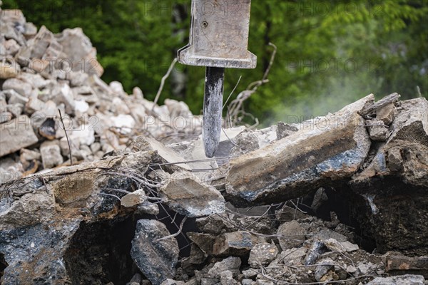 Excavator breaks up concrete and rubble and dust can be seen on a construction site, Demolition