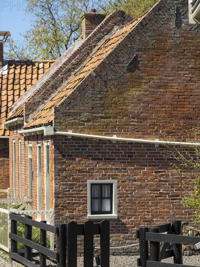A rustic brick building with a wooden fence and bricks, in a rural setting, enkhuizen, the