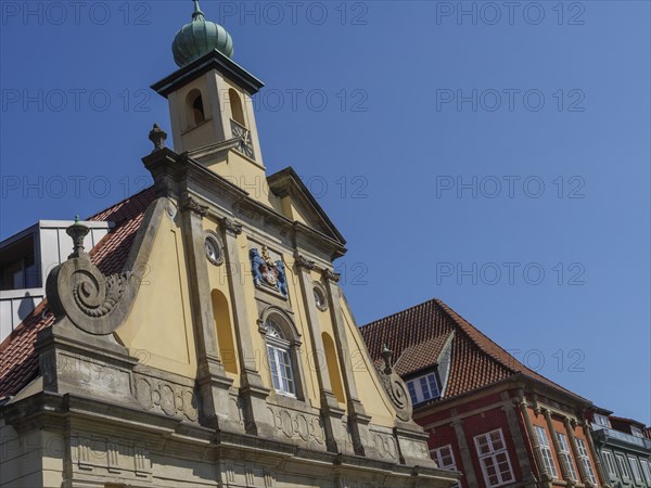 Baroque building in the old town centre with a pale church tower in the background under a blue