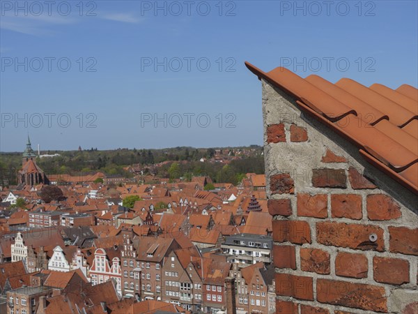 View over the red roofs of a city, calm and clear view with church tower in the background, view