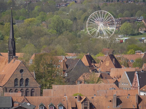 Cityscape with church tower, red roofs, green foliage and a holiday bike in the background under a