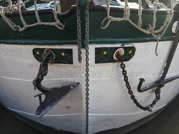 Close-up of a boat bow with anchor, chains and rope. Maritime decoration in green and white, Leer,