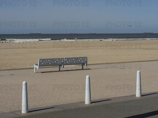Empty bench on the footpath along the beach, sea and ships on the horizon, scheveningen, the