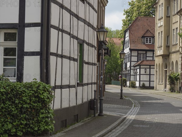 Historic half-timbered houses on a quiet, cobbled street with street lamps and green shutters,