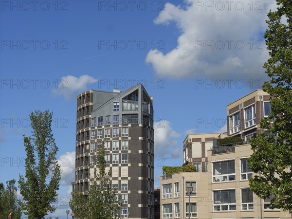 Tall, modern residential tower and neighbouring buildings in the middle of an urban landscape with