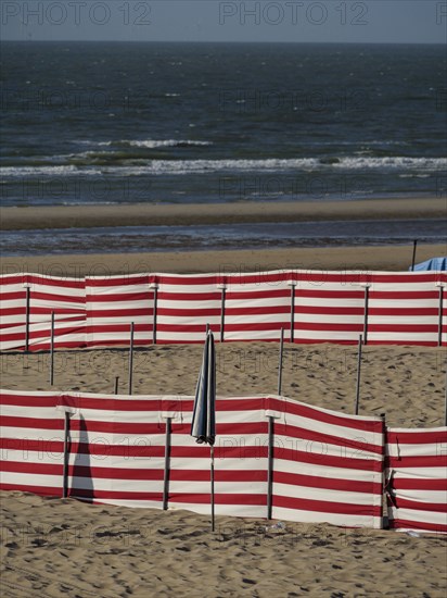 Beach landscape with red and white windbreaks and gentle waves in the background, de haan, Belgium,