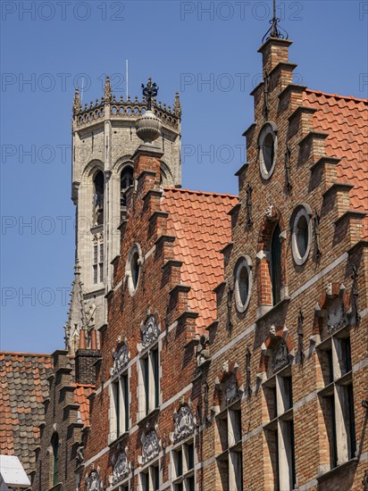 Historic brick buildings with ornate facades and a tall tower in the background, Bruges, Belgium,