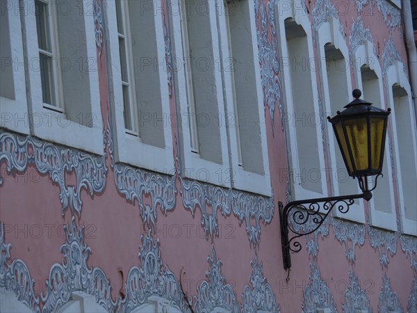 Pink baroque house facade with ornate windows and an old street lamp, trier, germany