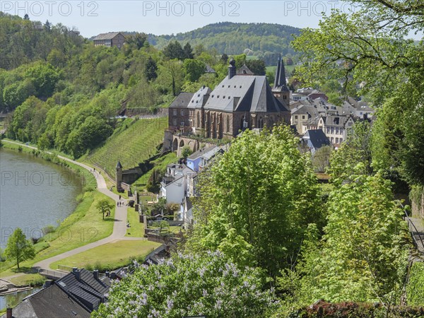 Idyllic view of a town with a river and green hills with historic buildings, Saarburg, Germany,