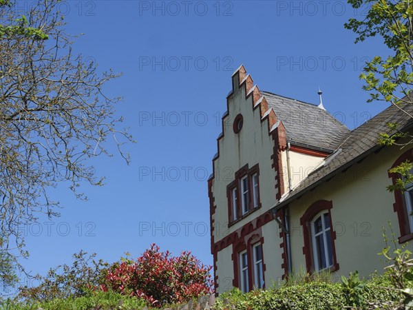 A house with striking architecture, surrounded by trees and plants under a blue sky, Saarburg,