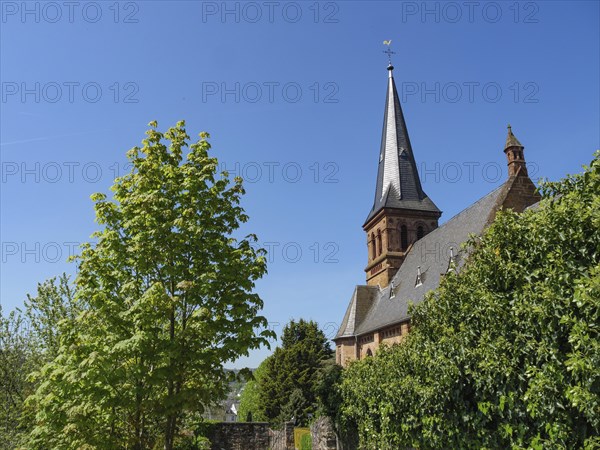 Church tower in a green, summery setting under a bright blue sky, Saarburg, Germany, Europe