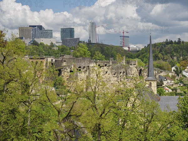 Ruins of a castle in front of a modern skyline with skyscrapers and green spaces, Luxembourg City,