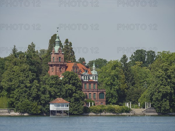 A castle with towers and red bricks, surrounded by trees on the lakeshore, Lindau, Lake Constance,