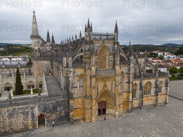 Impressive Gothic cathedral with a grand entrance and detailed towers under a cloudy sky, aerial