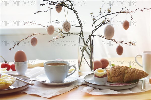 Easter breakfast in the morning sun with coffee and croissant on a table at the window, decoration